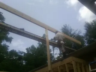 Carpenter setting a ridge beam over a new addition frame — Ice Dam Removal by Roofing Brothers in Foristell
