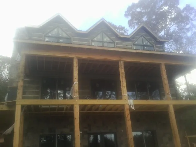 Dormers and porch framing on a large log home under construction — Roof Coating work by our crew in Foristell