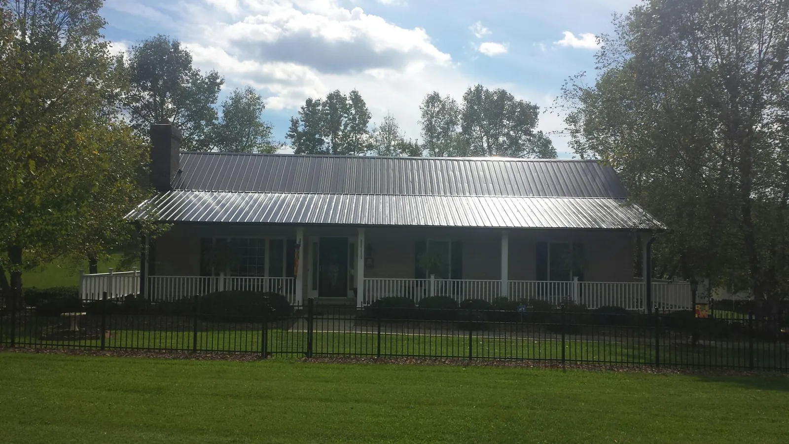 Gray metal roof on a brick ranch with a full width front porch — Gutter Guard Installation work by our crew in Foristell