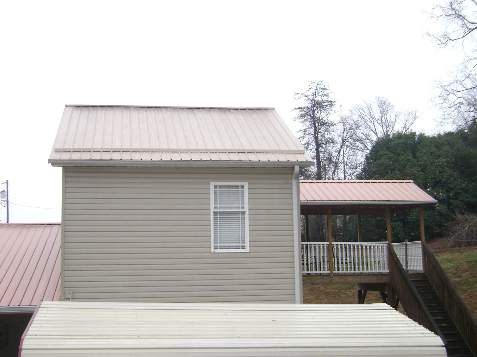 Tan metal roofs on a two story addition and attached porch, from a Roof Replacement job in Foristell