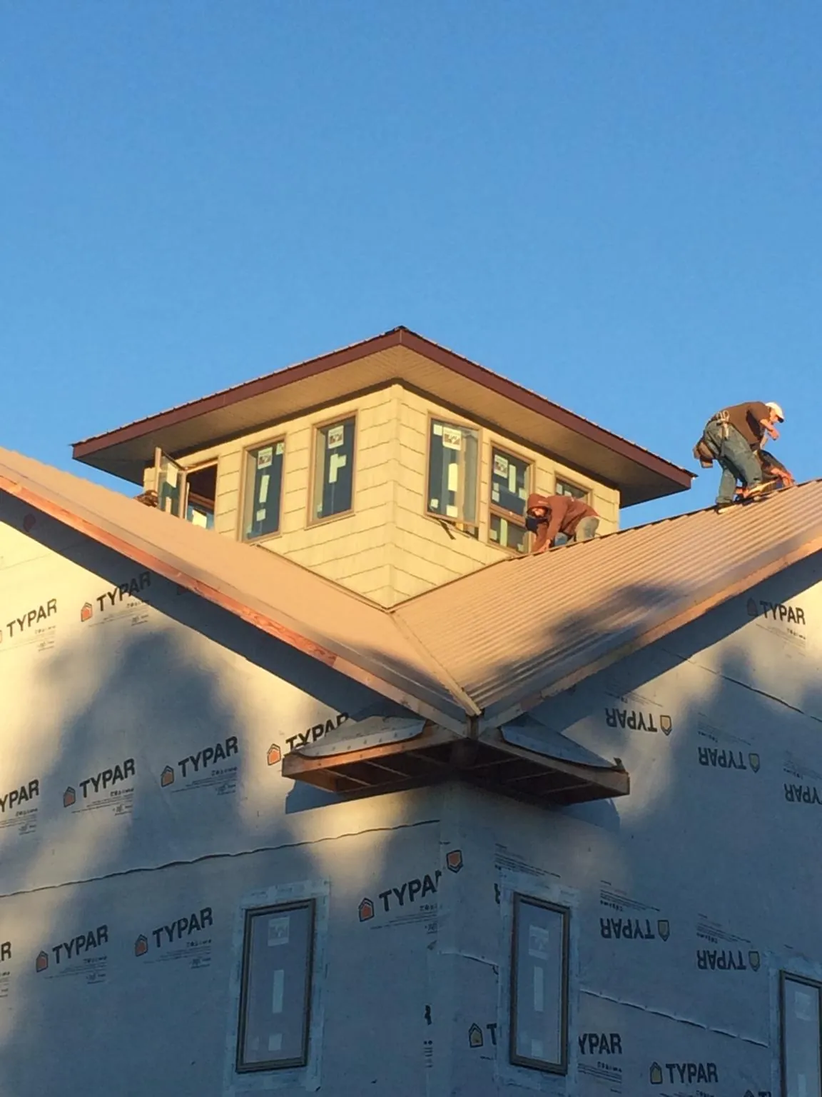 Roofers working around a rooftop cupola on a new metal roof at sunset — Roof Waterproofing in Foristell by Roofing Brothers